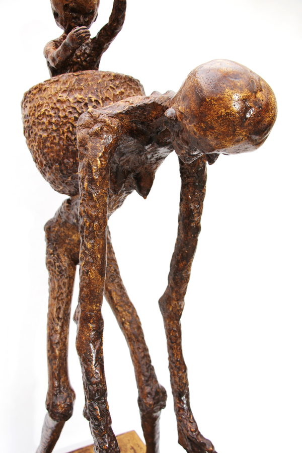 Close view of the bowed figure's head and shoulders, with the child and textured basket partly visible behind.