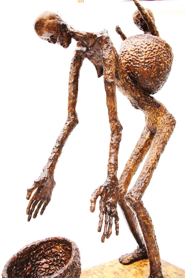 Opposite-side detail of the bowed figure, showing its extended hands, the basket on its back and part of the bowl below.