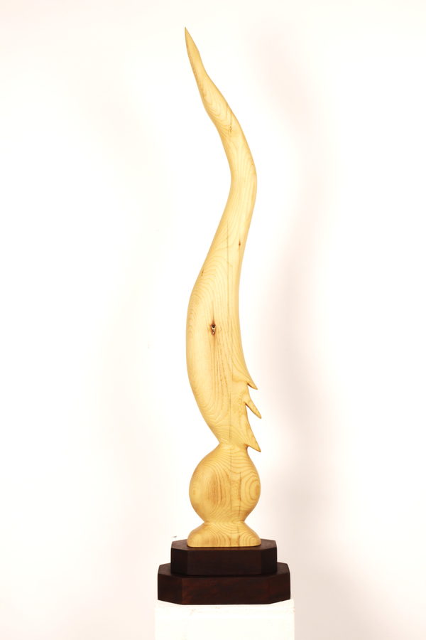 Bird on Egg, after Brâncuși (2023) by Valeriu Cazacevschi. A carved form in pale wood rising in a flame-like curve from an egg shape, on a dark stepped base.