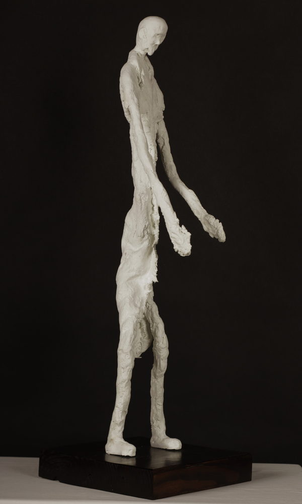 Elongated Sculpture by Valeriu Cazacevschi. Angled side view of the elongated figure, long hands and rectangular base.