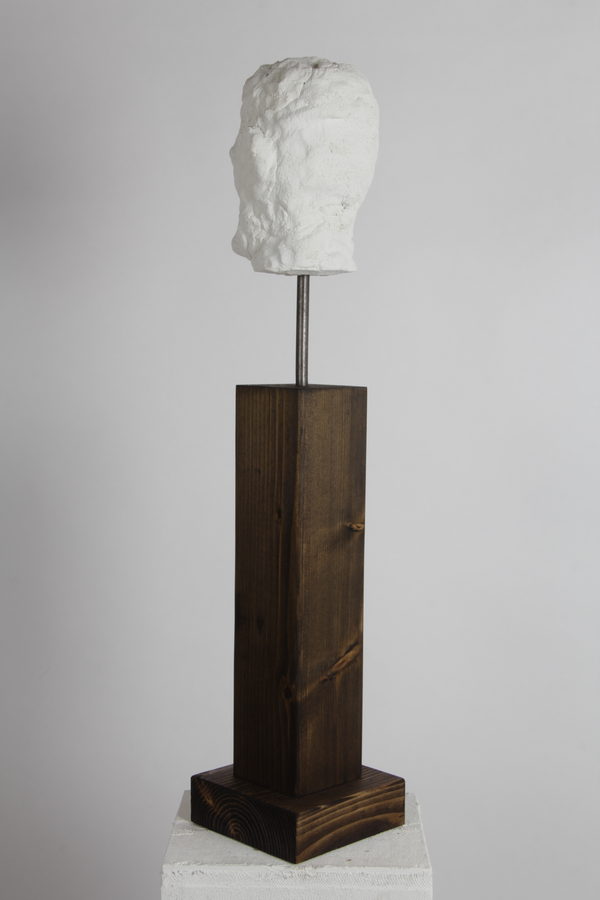 Head of an Old Man (2020) by Valeriu Cazacevschi. A white, roughly textured head on a metal rod above a tall dark wooden plinth.