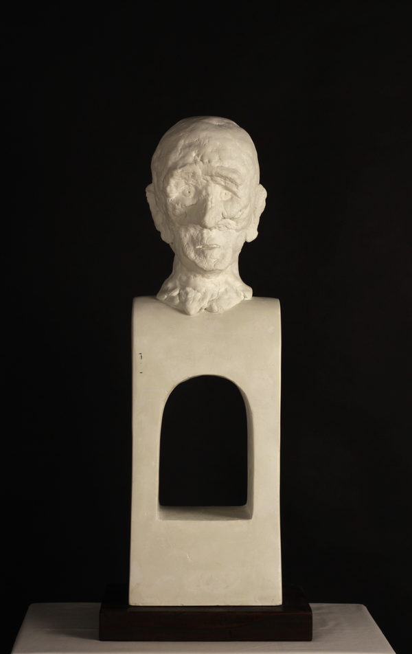 Hollow (2023) by Valeriu Cazacevschi. A pale sculpted head set on top of a rectangular block with an arched opening.