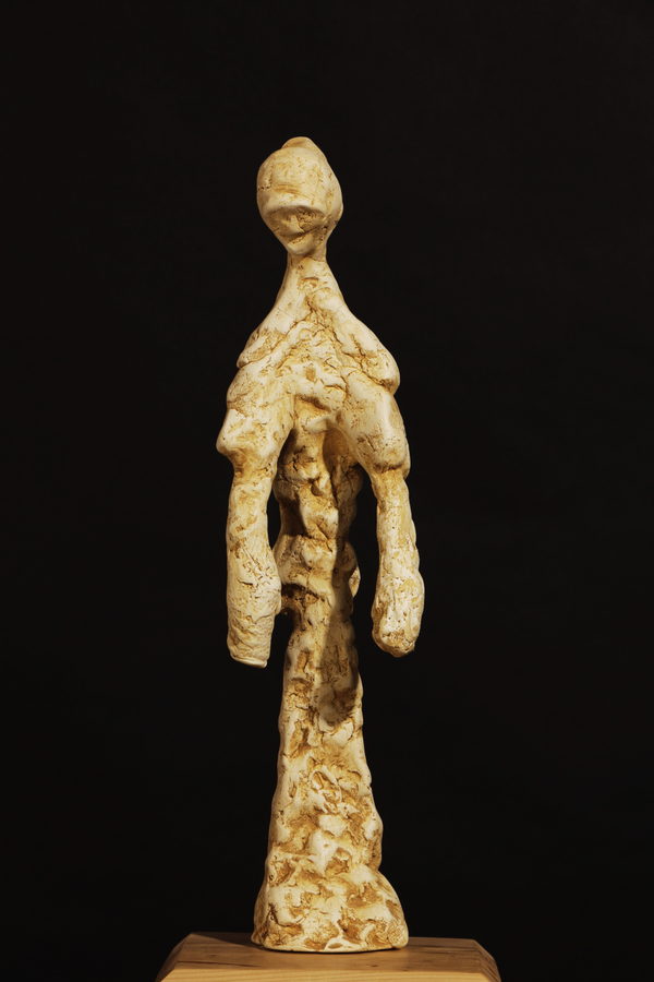 Humble Figure with Brown Patina by Valeriu Cazacevschi. A standing figure with a brown and gold patina over a draped, deeply textured surface, on a pale wooden block.