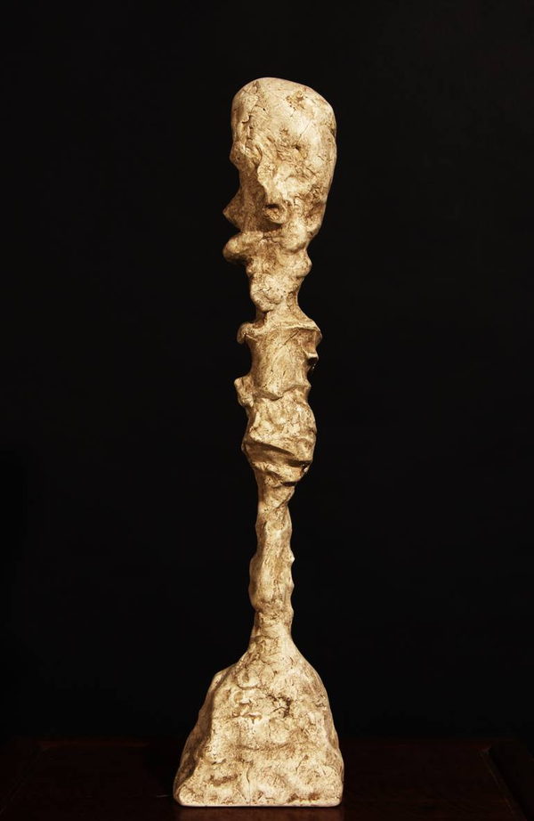 Profile view of the ochre head, textured slender stem and flared integral foot.