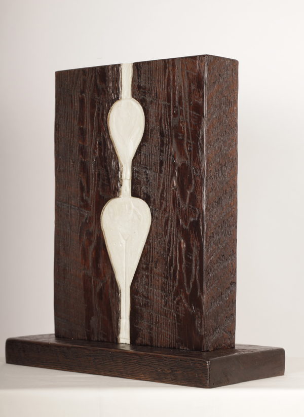 Two pale elongated forms set into a dark rectangular wooden composition.