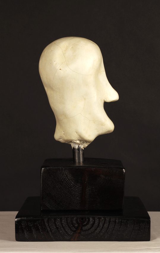 Pale sculpted head in profile on a dark wooden base