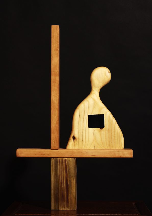 Small wooden figure set beside upright and horizontal wooden beams