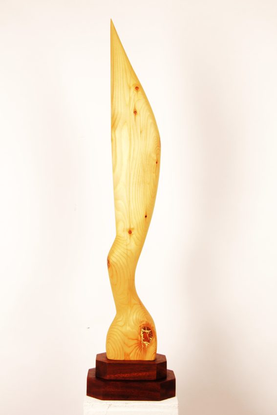 Tall curved carved wooden sculpture on a dark stepped base